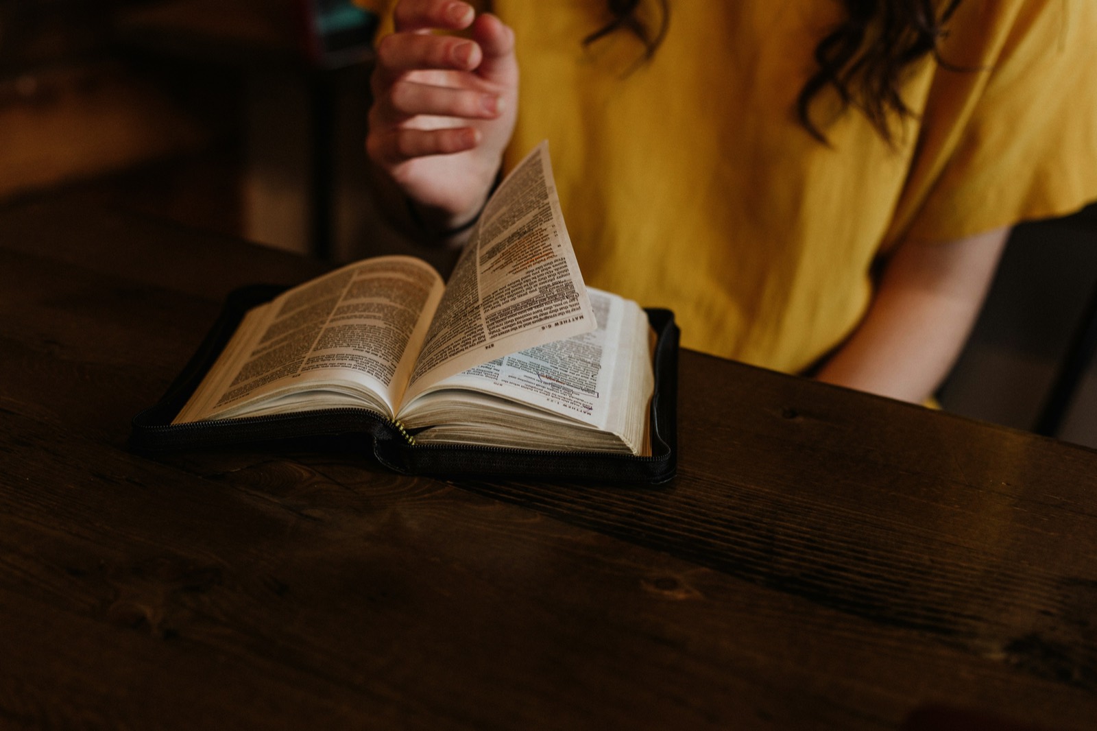 An open Bible being read at a wooden table